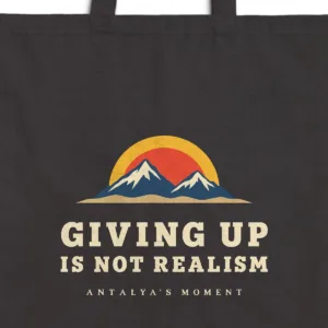 Close-up of the Giving Up Is Not Realism Night design printed on a black canvas tote, with the top seam and handles