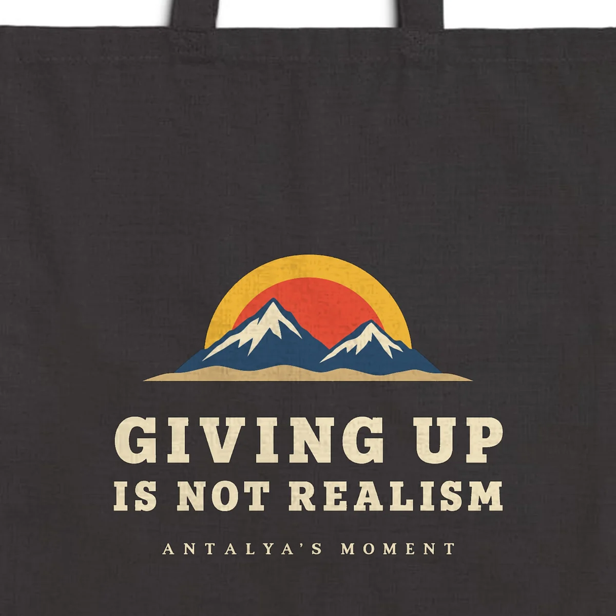 Close-up of the Giving Up Is Not Realism Night design printed on a black canvas tote, with the top seam and handles