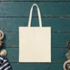 Plain back of the natural canvas tote with the Giving Up Is Not Realism design, printed on the front only