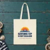 Giving Up Is Not Realism design on a natural canvas tote, laid flat