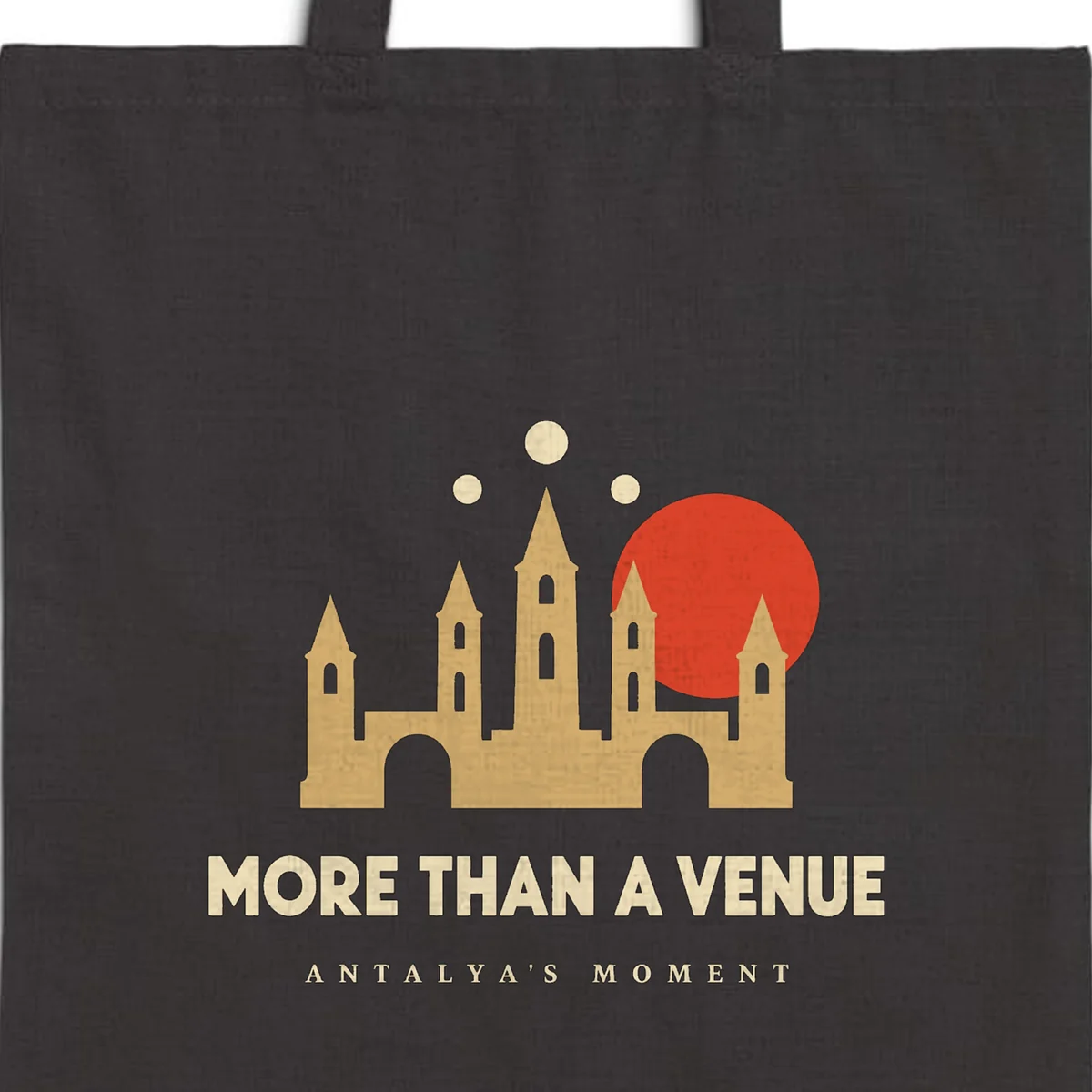 Close-up of the More Than a Venue Night design printed on a black canvas tote, with the top seam and handles