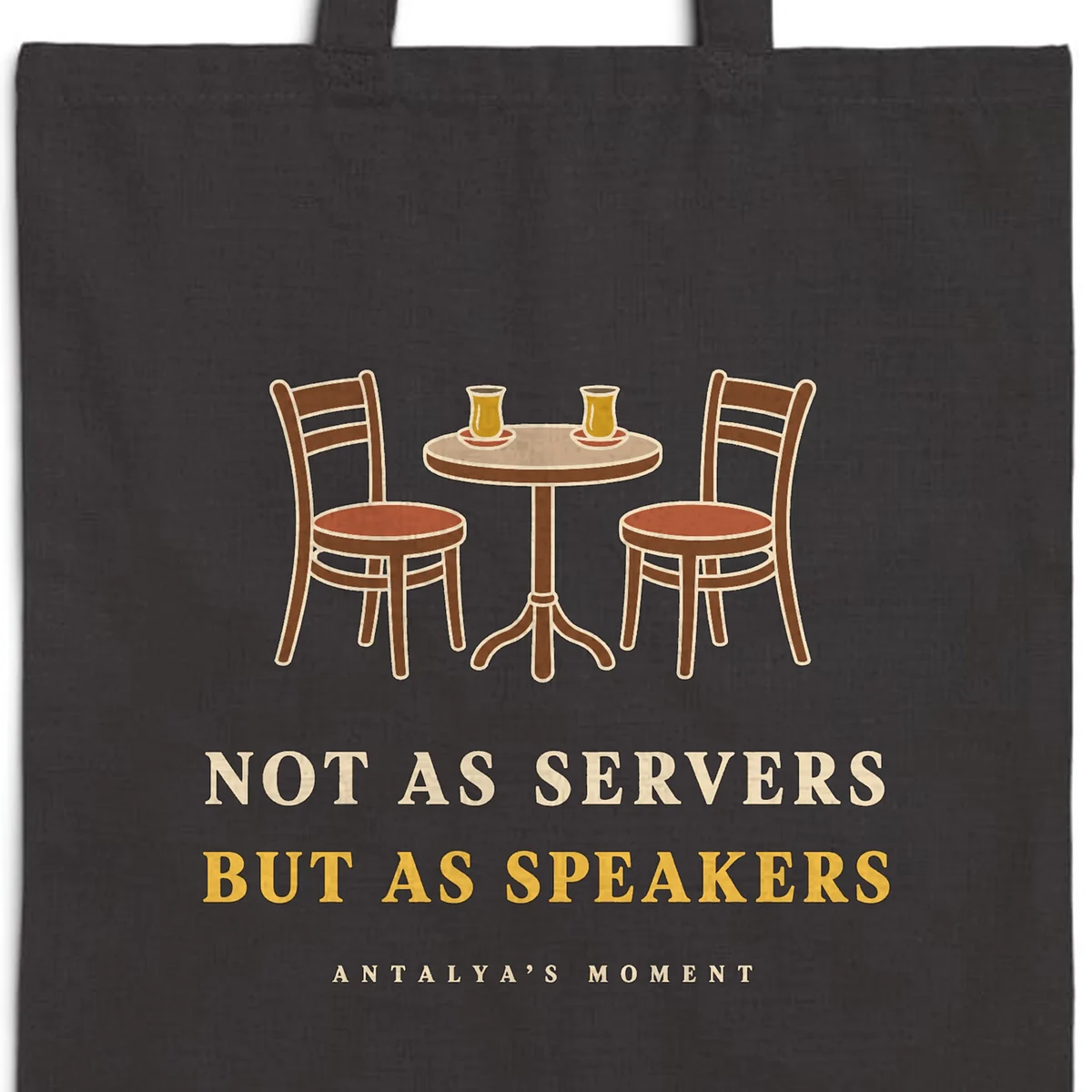 Close-up of the Not as Servers, but as Speakers Night design printed on a black canvas tote, with the top seam and handles