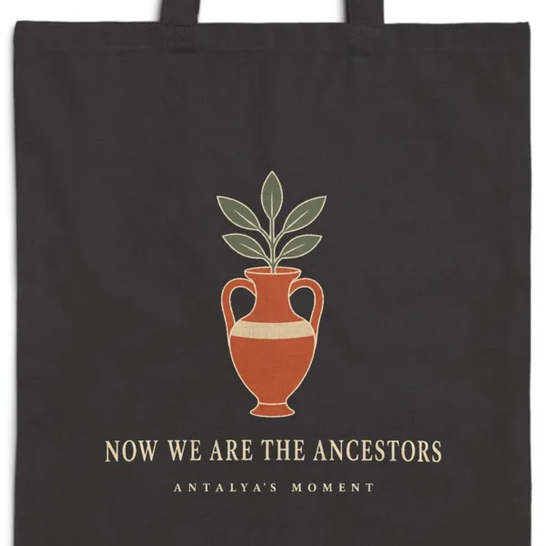 Close-up of the Now We Are the Ancestors Night design printed on a black canvas tote, with the top seam and handles