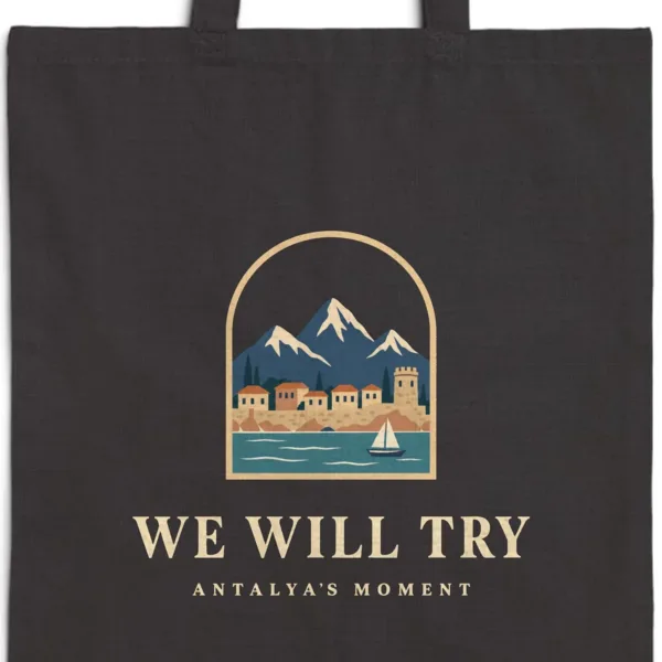 we-will-try-night-tote-black-detail-v1 Close-up of the We Will Try Night design printed on a black canvas tote, with the top seam and handles